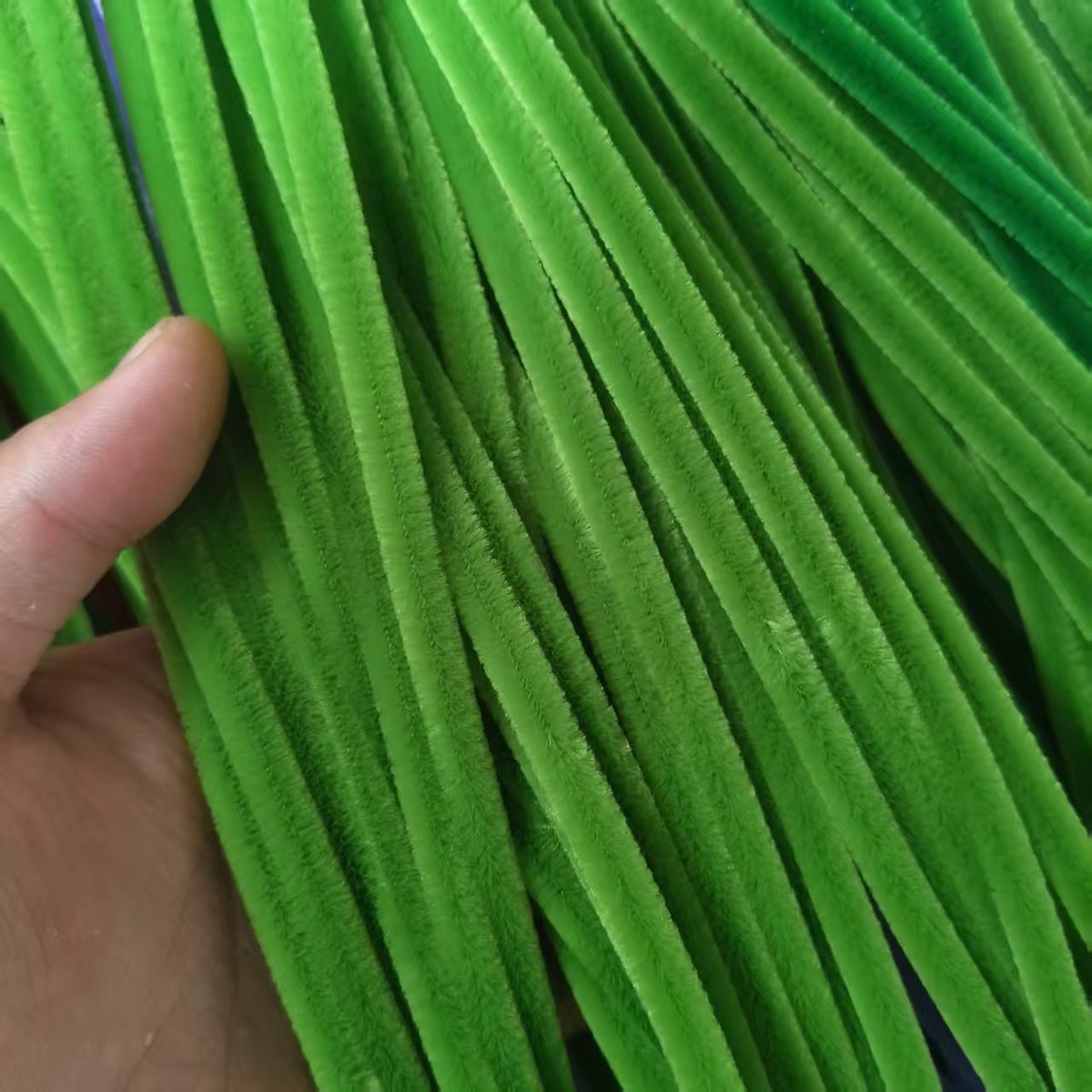 Close-up quality check of green chenille stems
